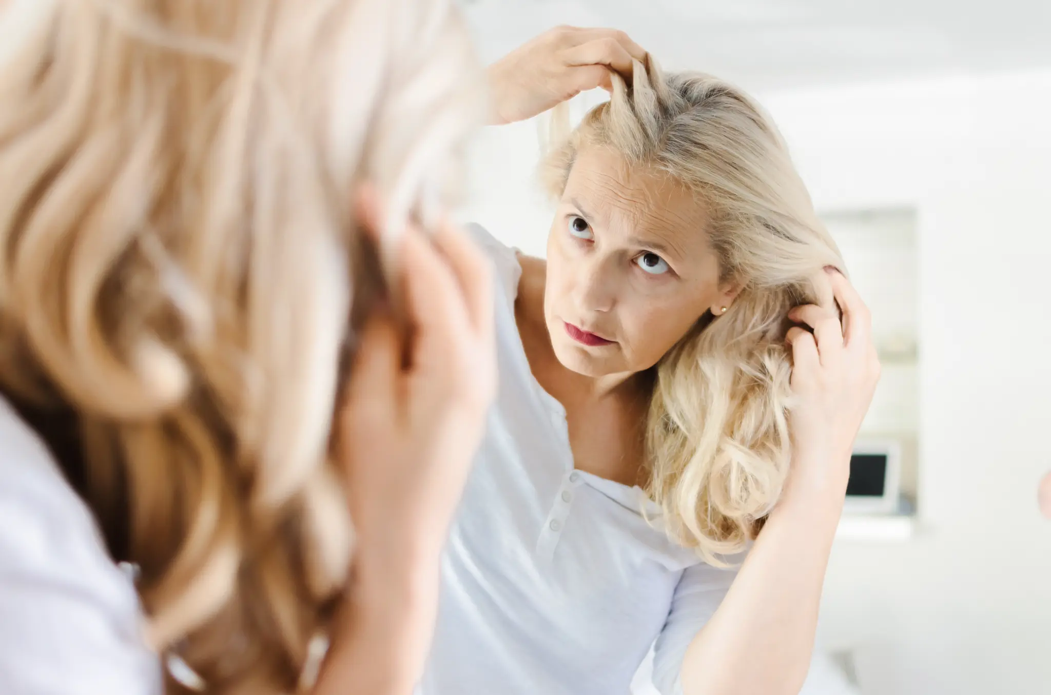 Woman examining hair thinning in mirror